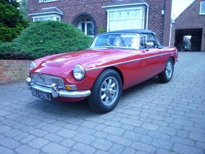 Red classic MG roadster outside a house